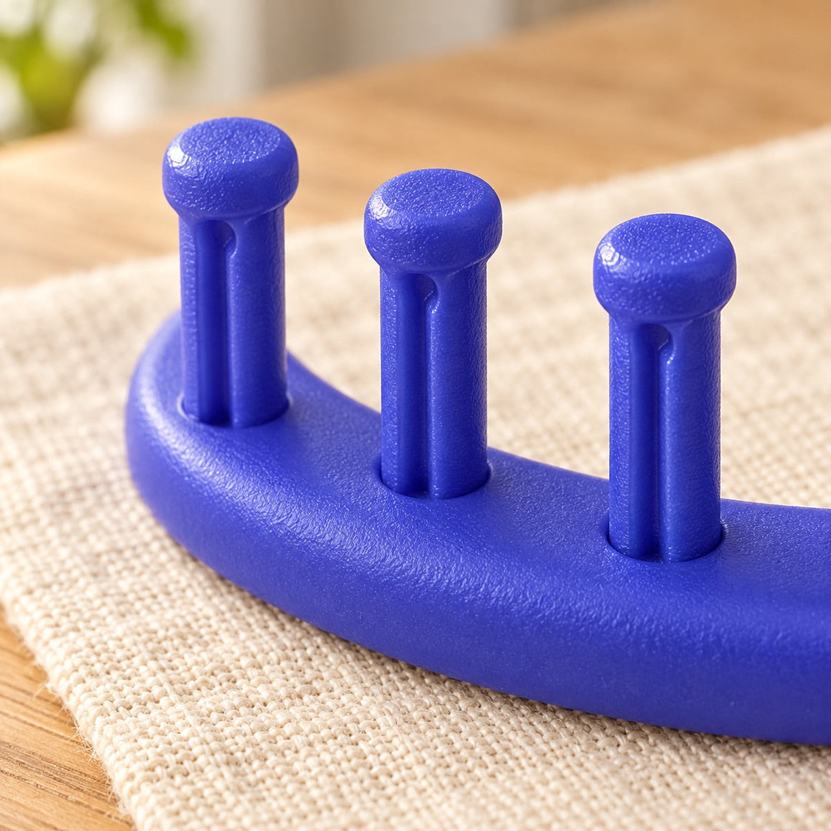AI-styled: Macro detail of three pegs on the blue round knitting loom. Styling props are not included.