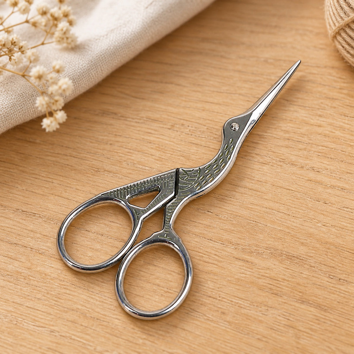 AI-styled: Silver Stork Embroidery Scissors on a warm oak craft desk. Styling props are not included.