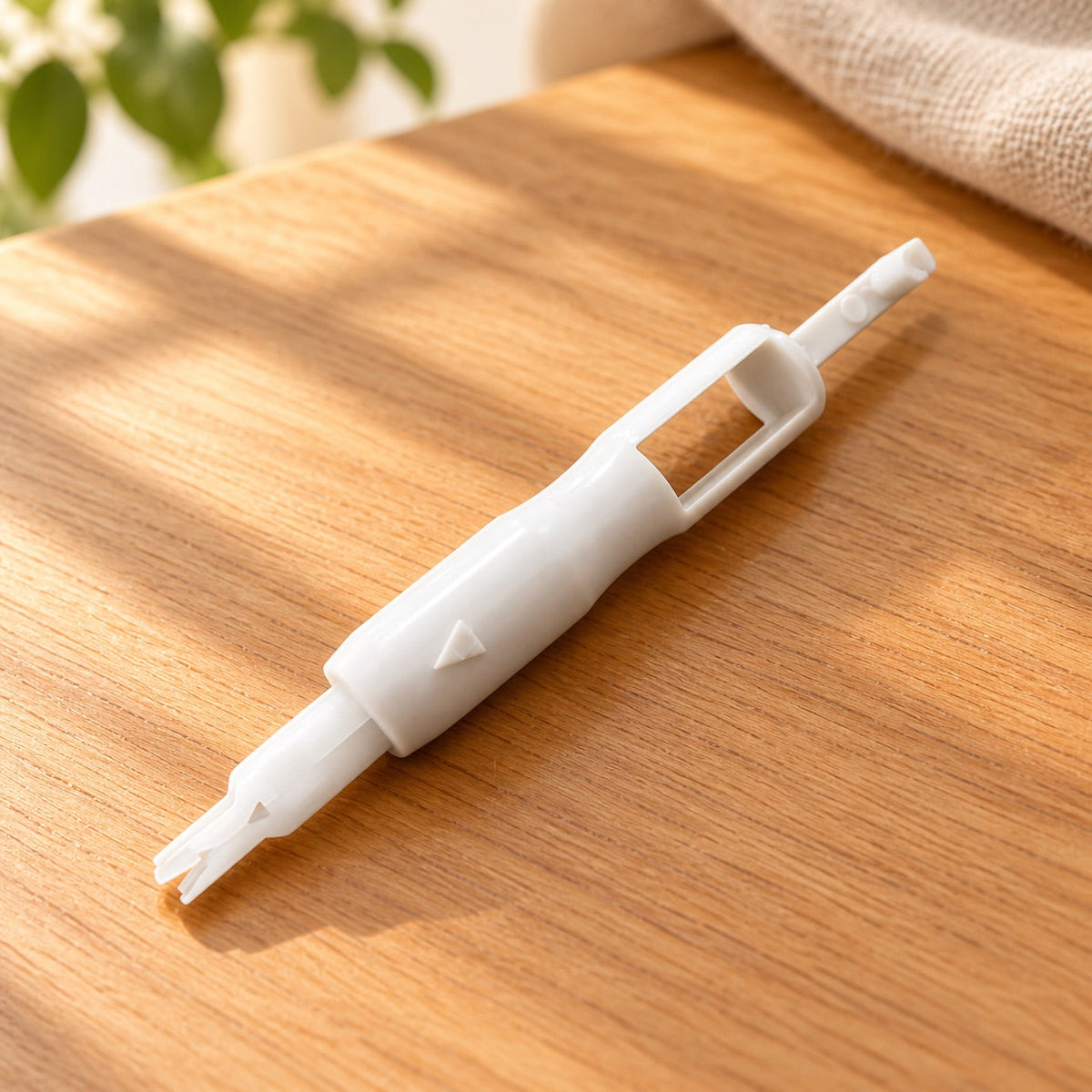 AI-styled: One white sewing machine needle threader from the nine-piece set on a warm oak worktable. Styling props are not included.